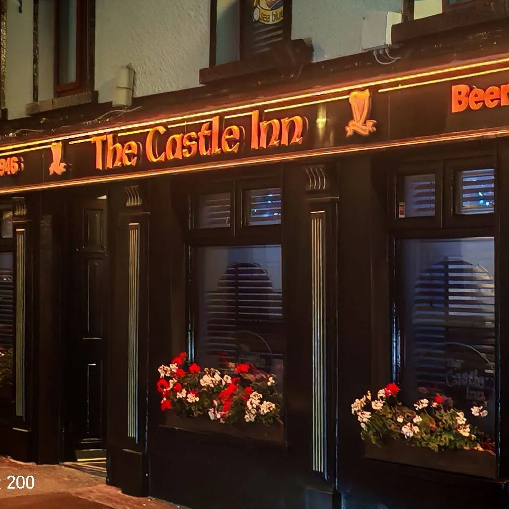 The Castle Inn at night with illuminated signage, amber glow, and flower boxes